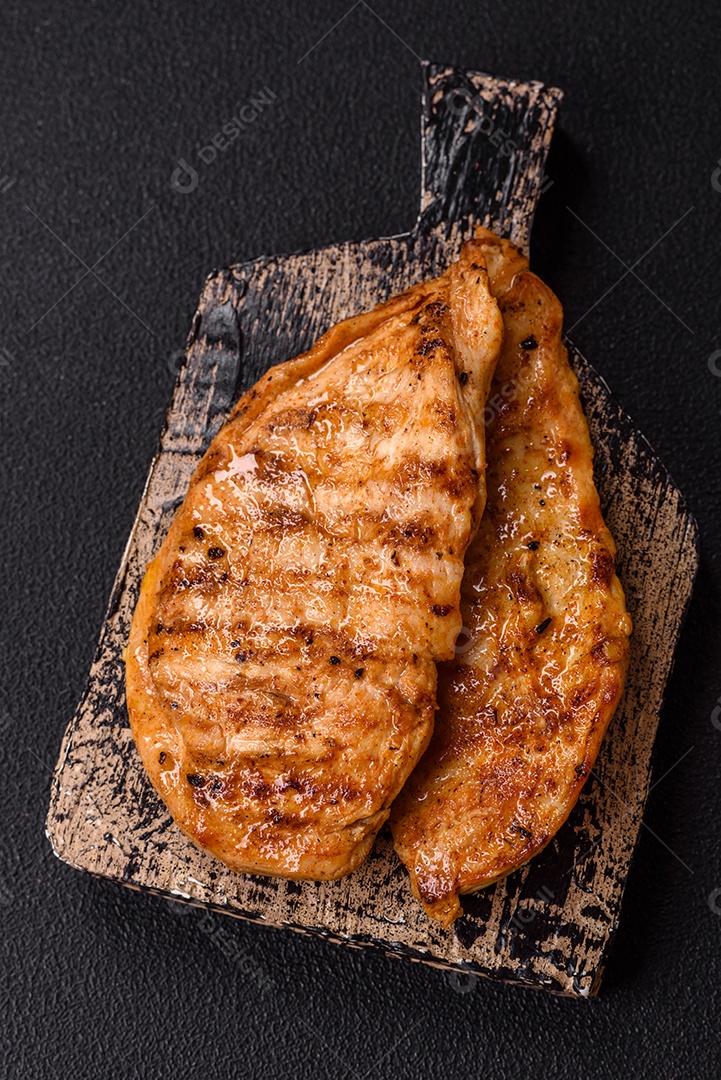 A imagem mostra filés de frango grelhados, acompanhados de temperos e tomates cereja.