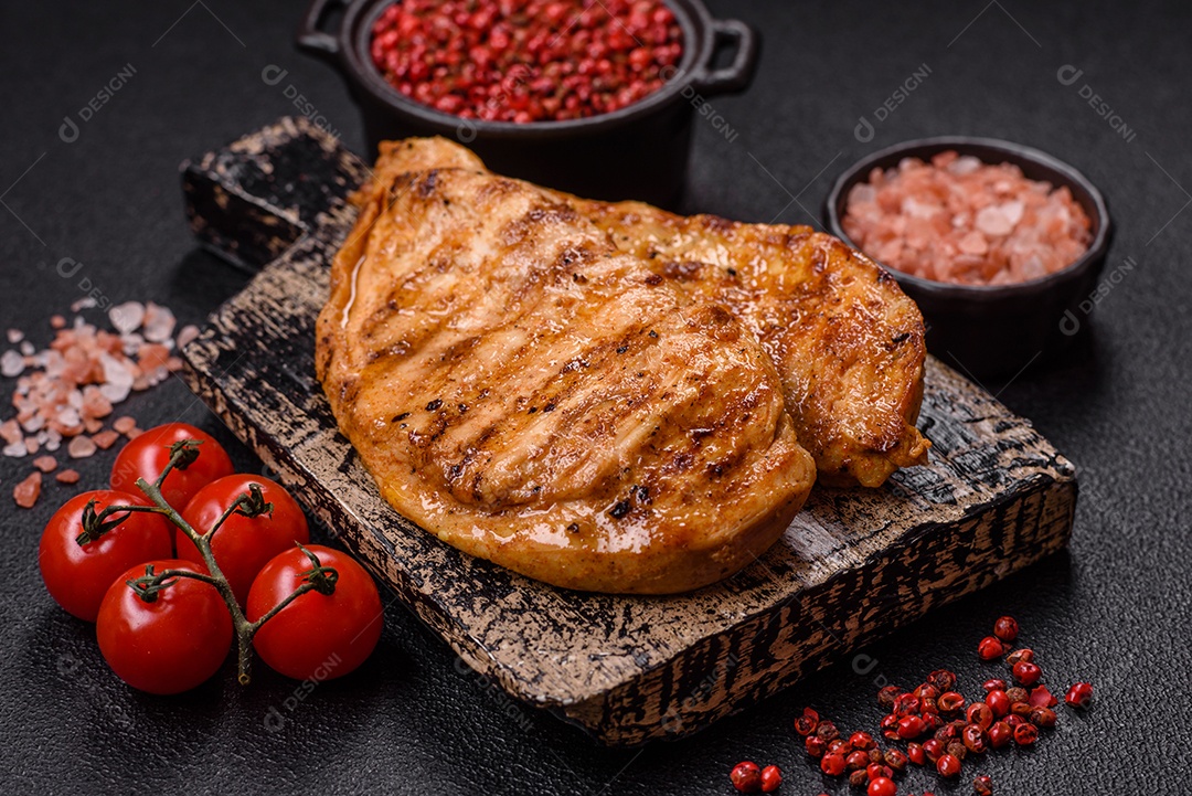 A imagem mostra filés de frango grelhados, acompanhados de temperos e tomates cereja.