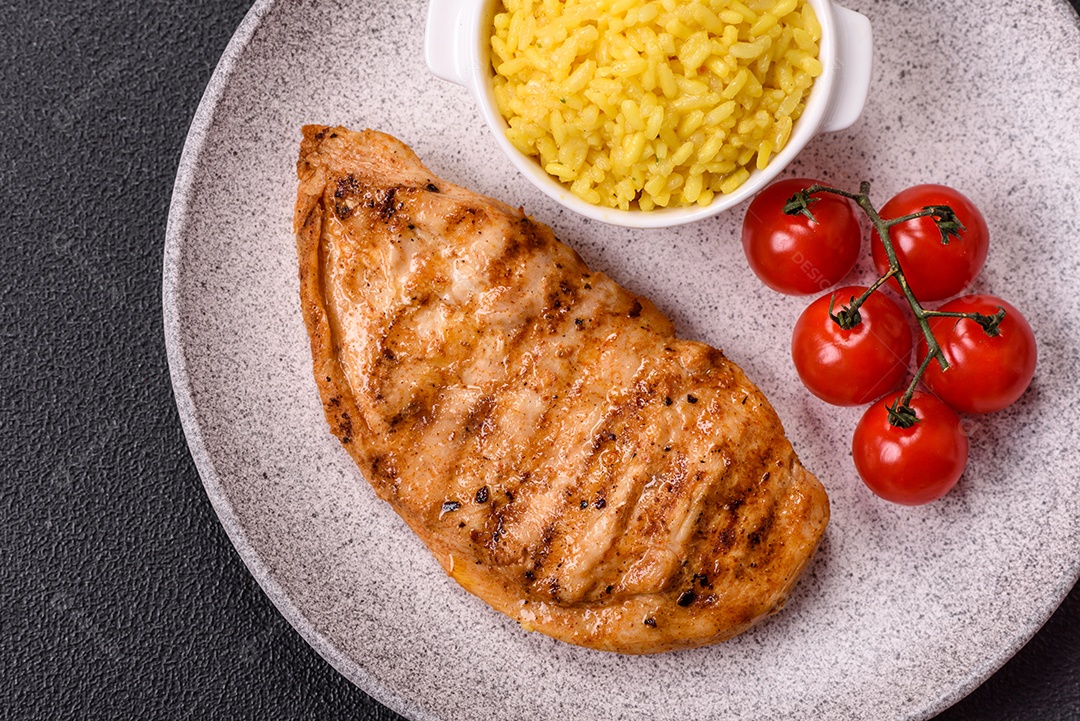 A imagem mostra filés de frango grelhados, acompanhados de temperos e tomates cereja.