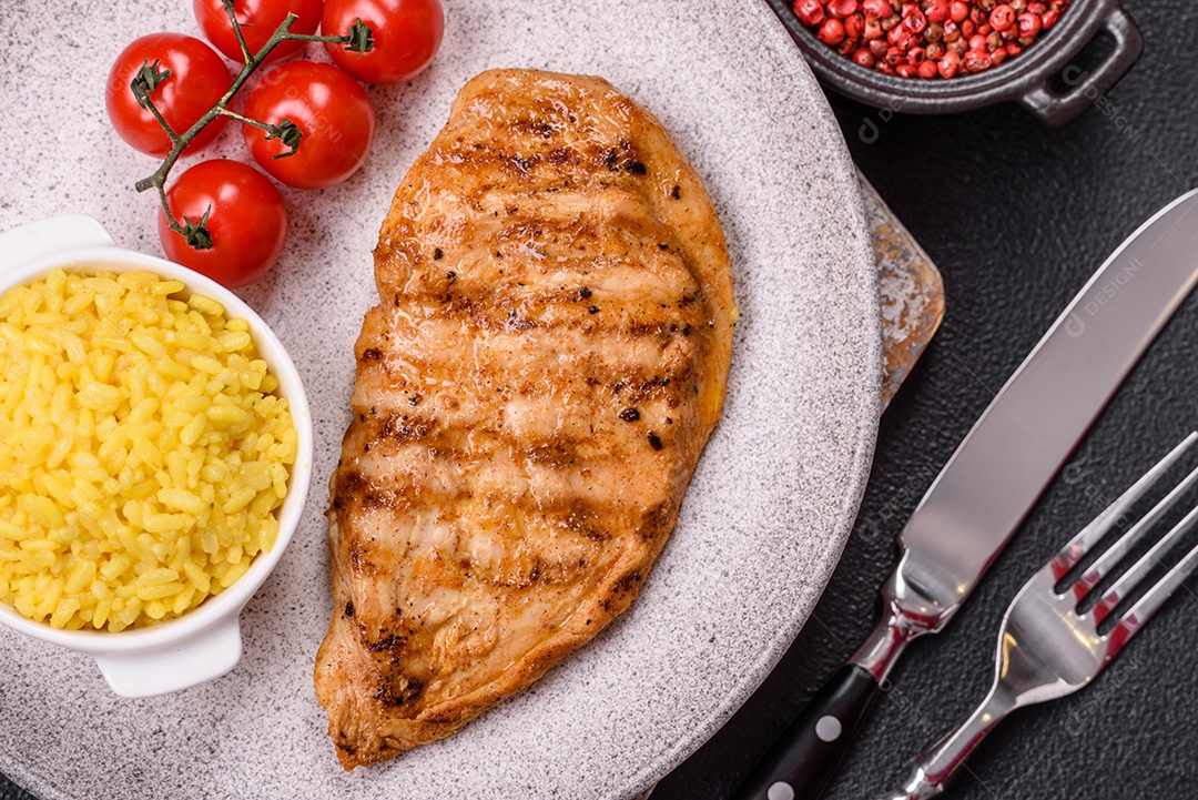A imagem mostra filés de frango grelhados, acompanhados de temperos e tomates cereja.