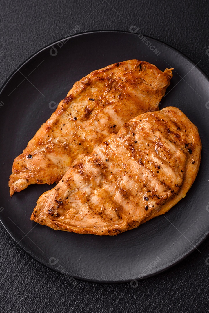 A imagem mostra filés de frango grelhados, acompanhados de temperos e tomates cereja.