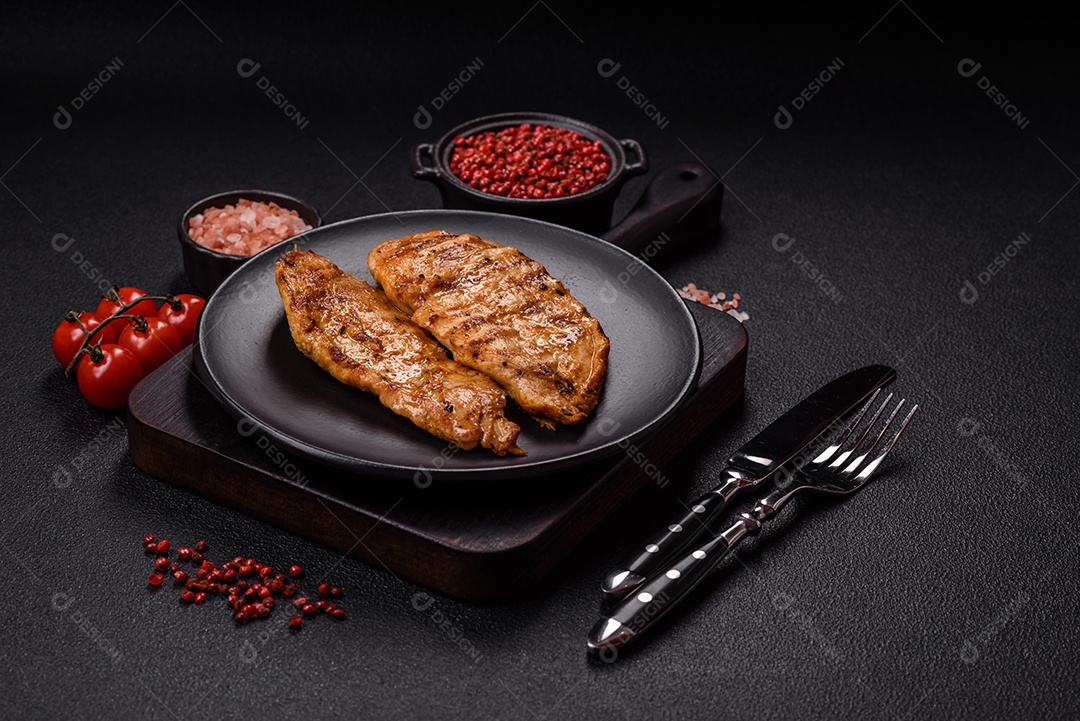 A imagem mostra filés de frango grelhados, acompanhados de temperos e tomates cereja.