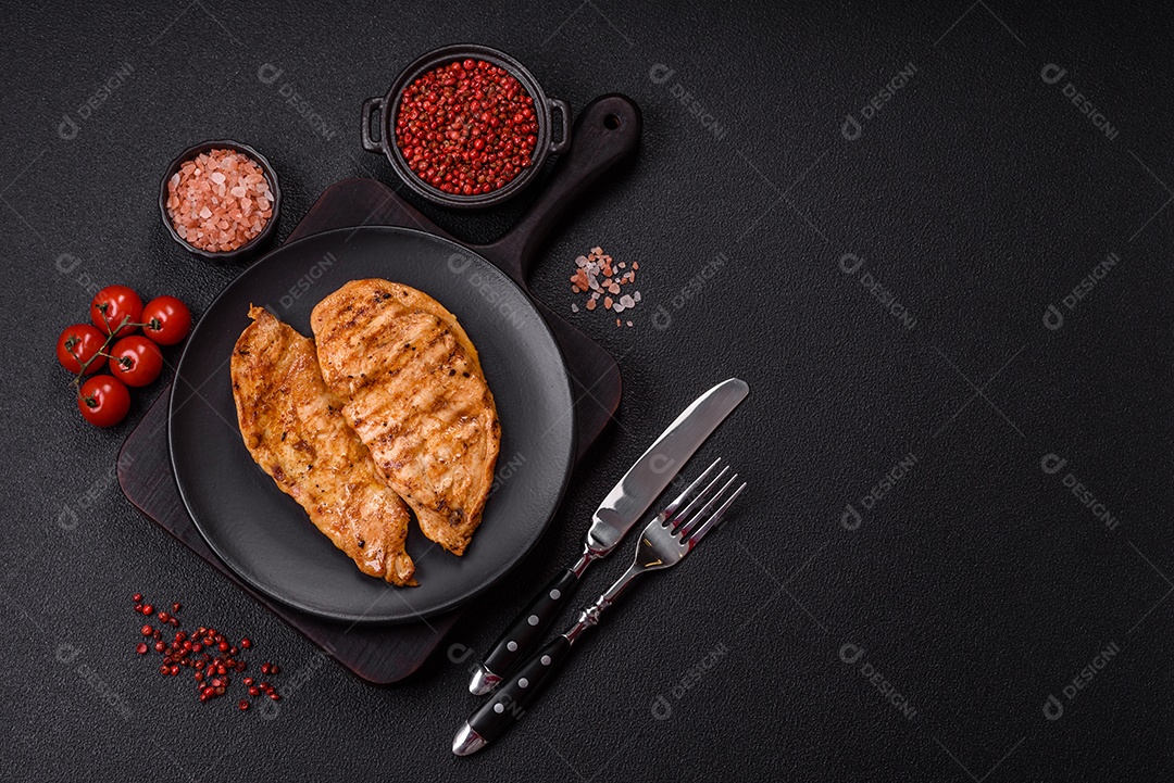 A imagem mostra filés de frango grelhados, acompanhados de temperos e tomates cereja.