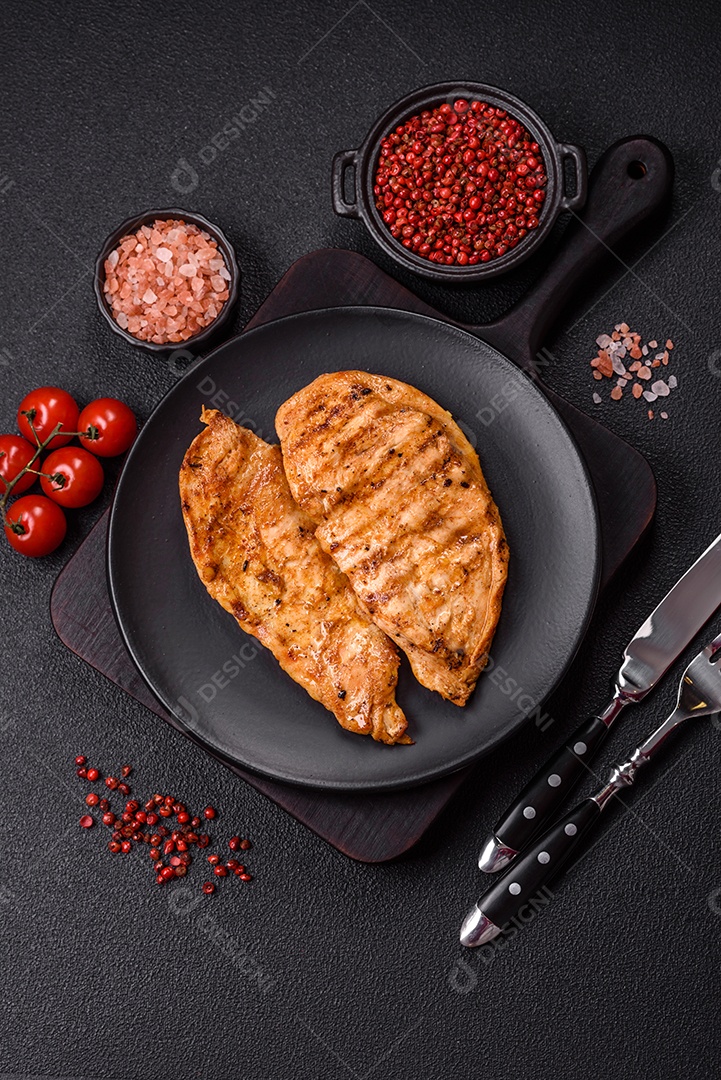 A imagem mostra filés de frango grelhados, acompanhados de temperos e tomates cereja.