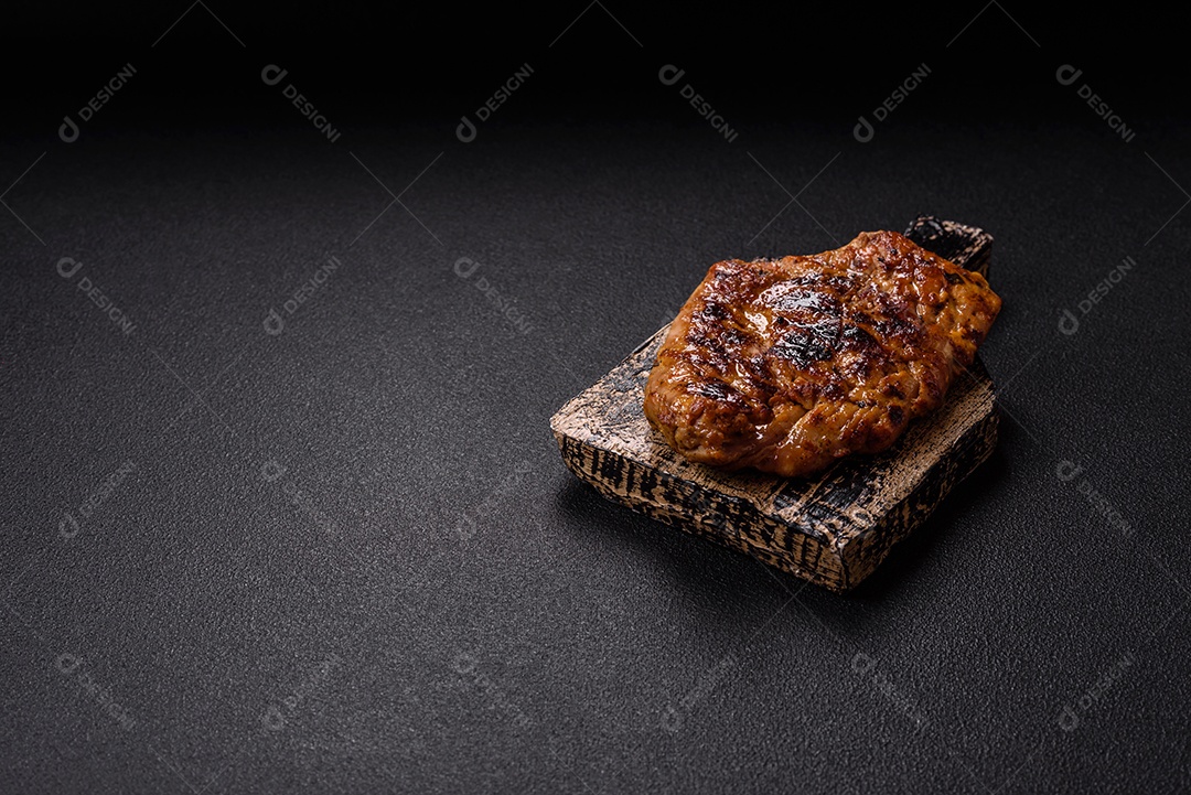 A imagem mostra um pedaço de carne grelhada ou assada, possivelmente frango ou porco, servido em uma tábua de madeira