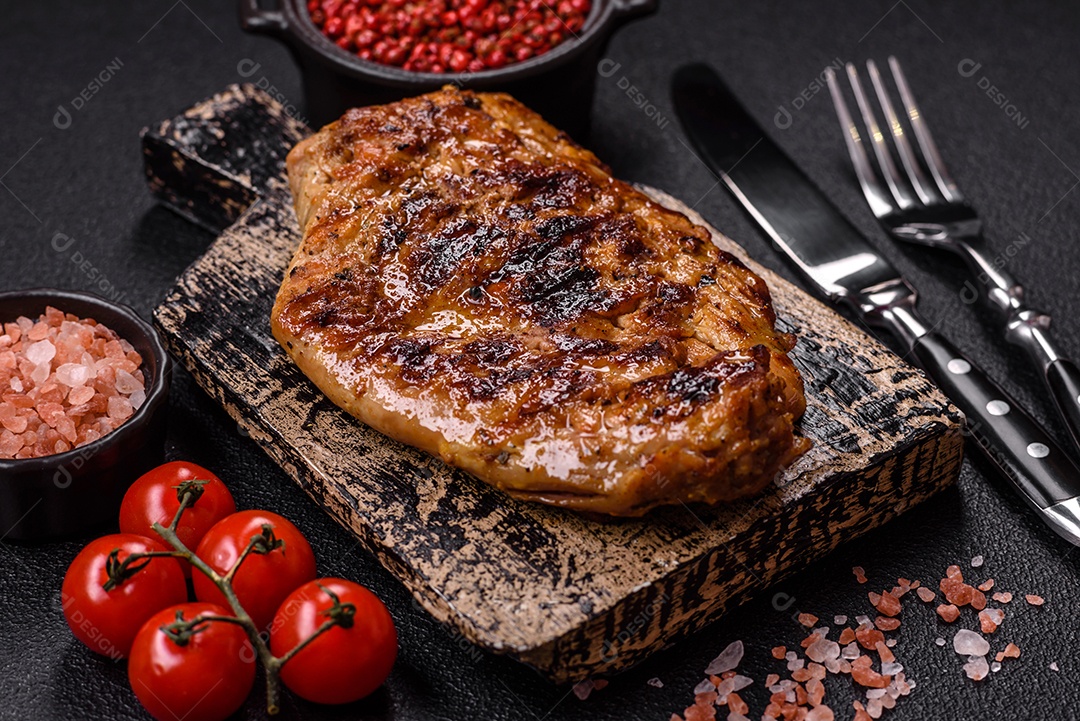 A imagem mostra um pedaço de carne grelhada ou assada, possivelmente frango ou porco, servido em uma tábua de madeira