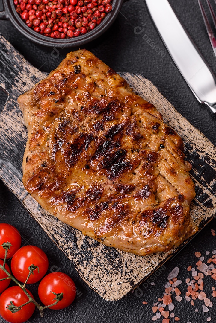 A imagem mostra um pedaço de carne grelhada ou assada, possivelmente frango ou porco, servido em uma tábua de madeira
