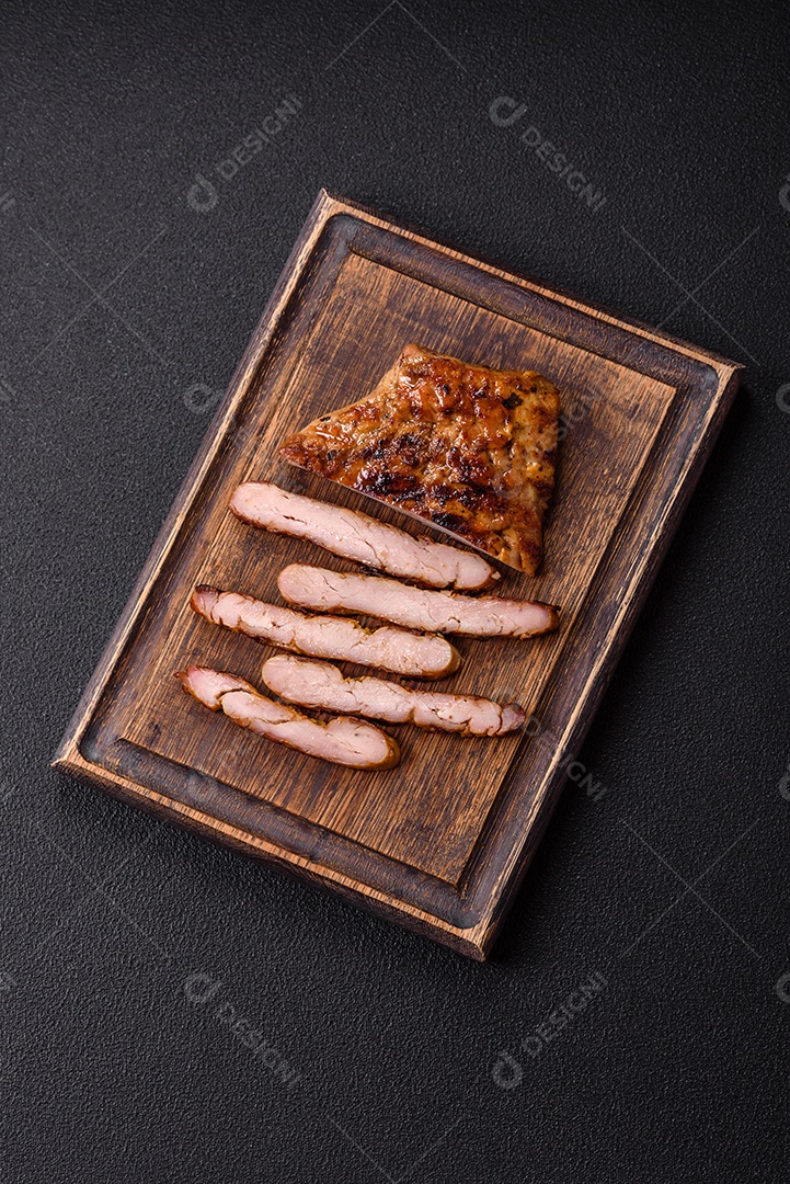 A imagem mostra um pedaço de carne grelhada ou assada, possivelmente frango ou porco, servido em uma tábua de madeira