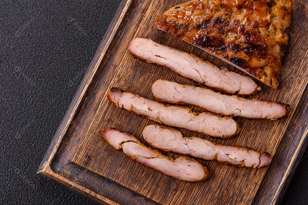 A imagem mostra fatias de carne de porco grelhada, provavelmente lombo ou um corte similar, servidas em uma tábua de madeira.