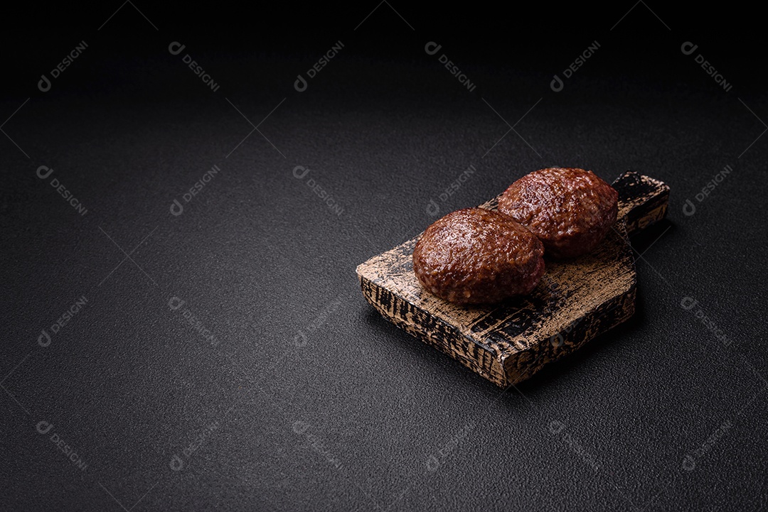 A imagem mostra dois hambúrgueres (ou bifes de carne moída) em um prato preto, acompanhados por tomates cereja