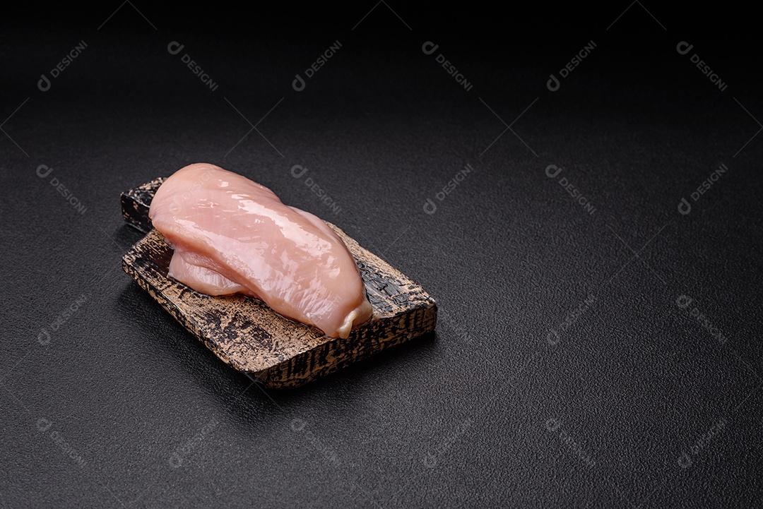 A imagem mostra dois filés de peito de frango crus sobre uma tábua de madeira