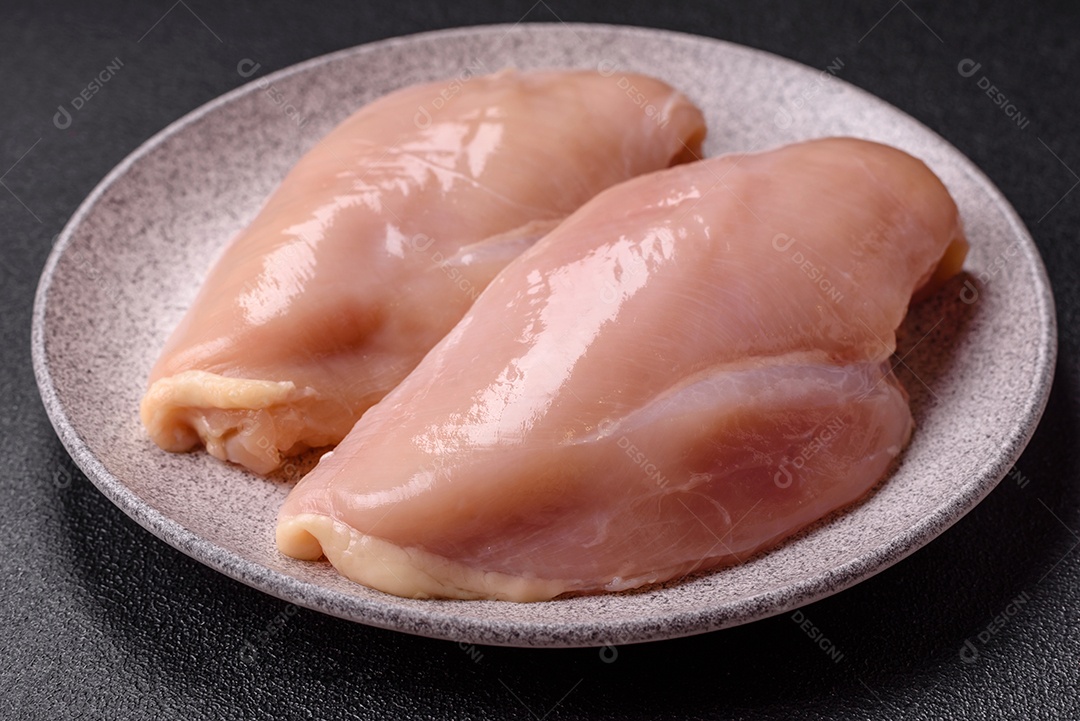 A imagem mostra dois filés de peito de frango crus sobre uma tábua de madeira