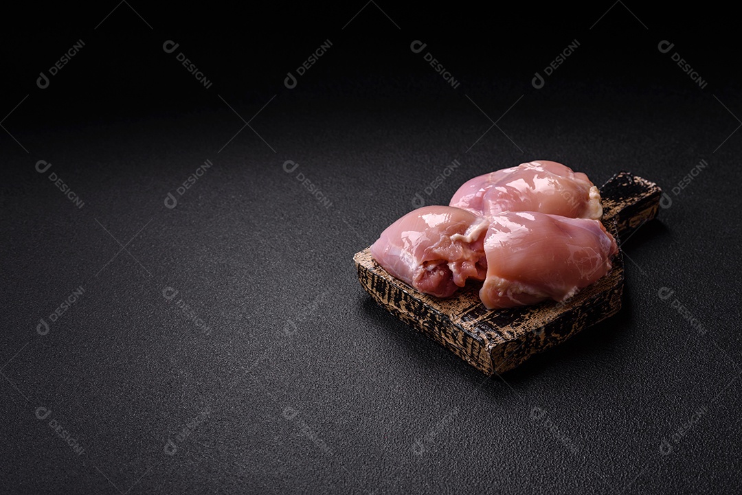 A imagem mostra dois filés de peito de frango crus sobre uma tábua de madeira