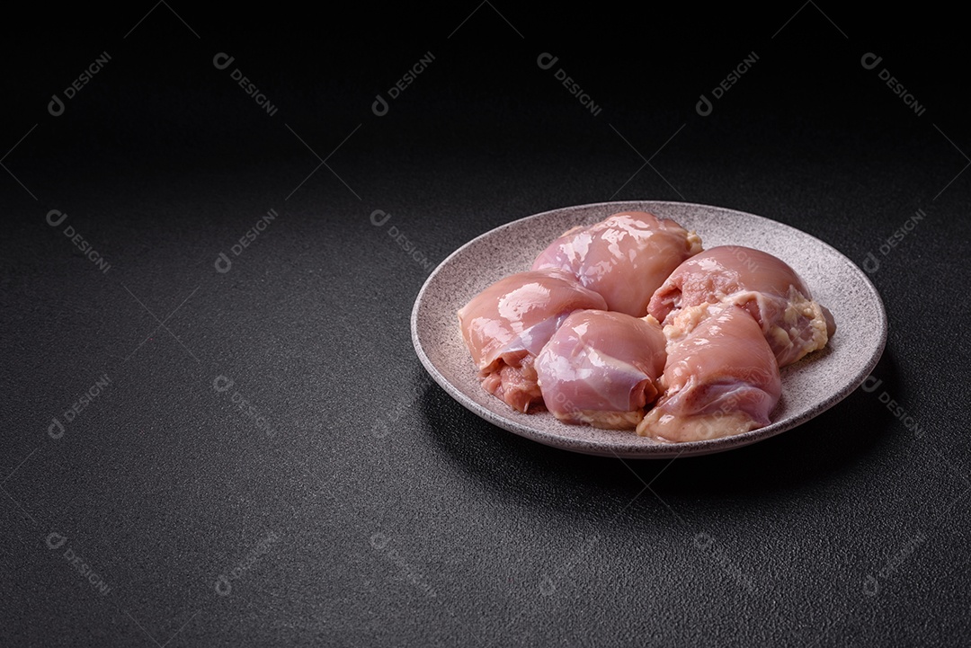 A imagem mostra sobrecoxas de frango cruas em um prato.