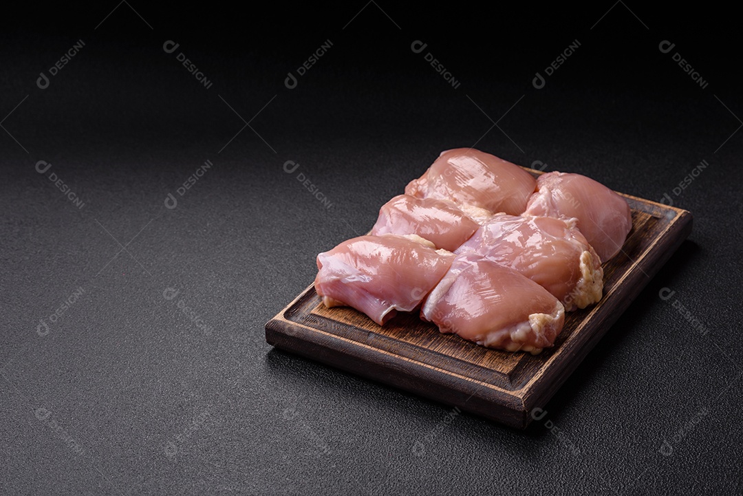 A imagem mostra dois filés de peito de frango crus sobre uma tábua de madeira