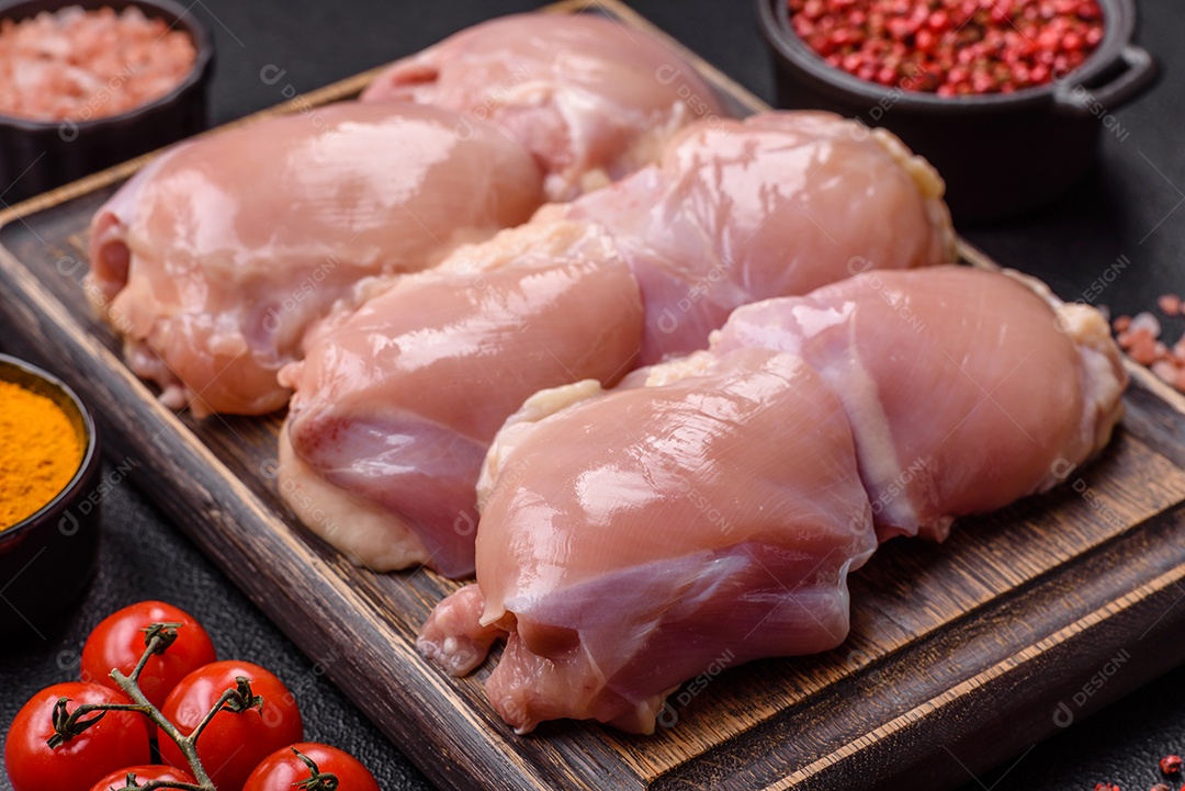 A imagem mostra dois filés de peito de frango crus sobre uma tábua de madeira