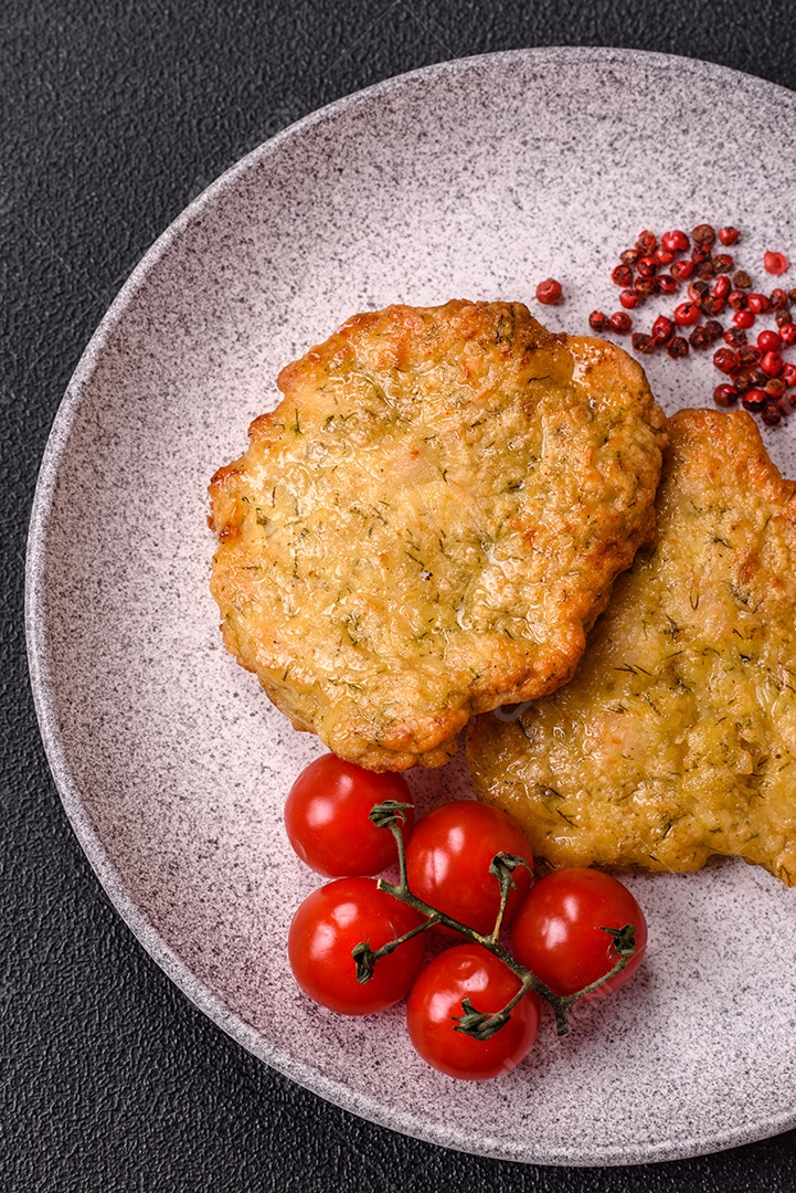 A imagem mostra pedaços de frango frito, acompanhados por tomates cereja e pimenta rosa.