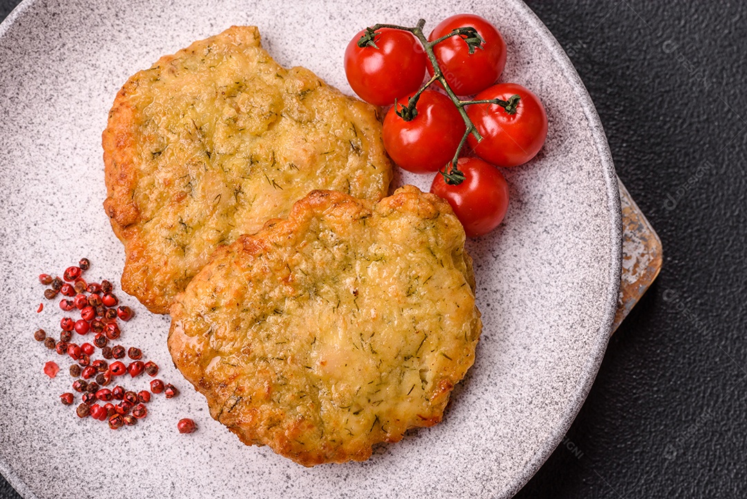 A imagem mostra pedaços de frango frito, acompanhados por tomates cereja e pimenta rosa.