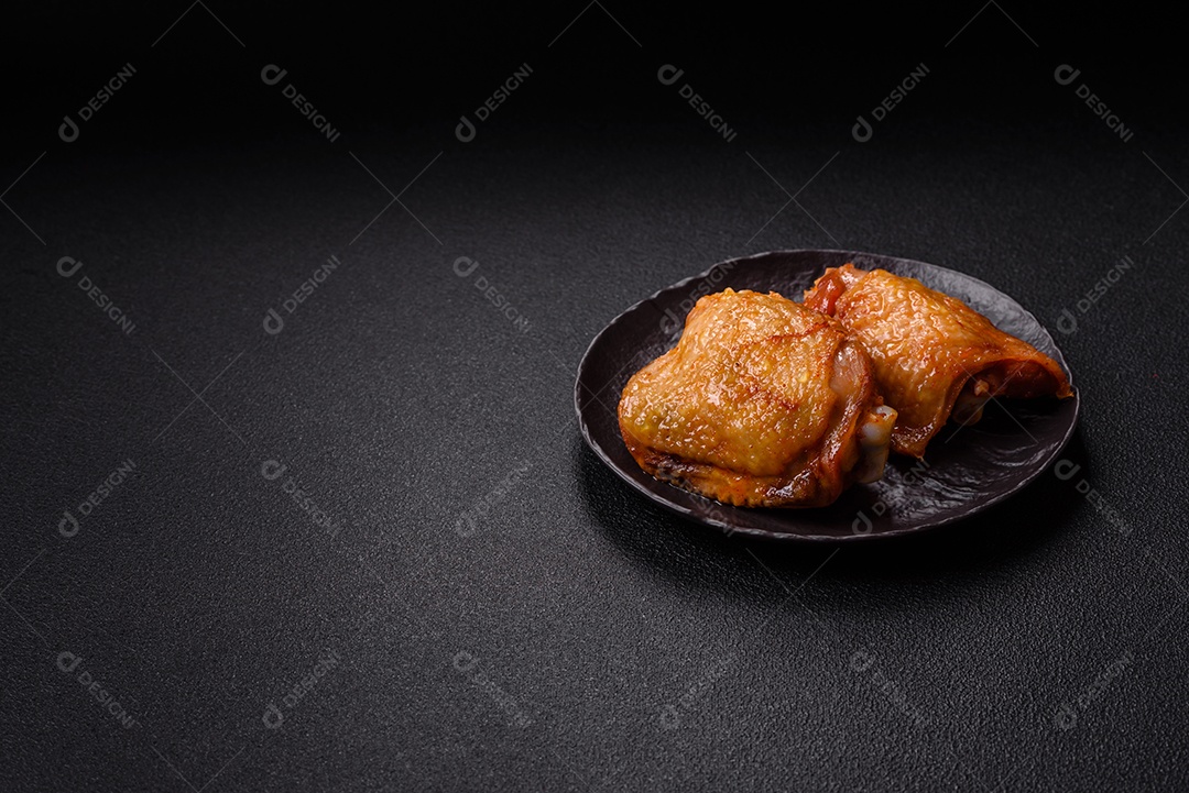 A imagem mostra sobrecoxas de frango ou coxas de frango em um prato escuro