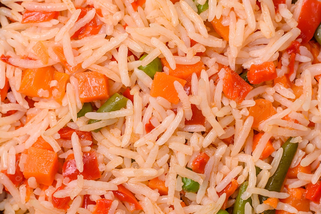 A imagem mostra um prato de arroz cozido com vegetais, como cenoura e vagem