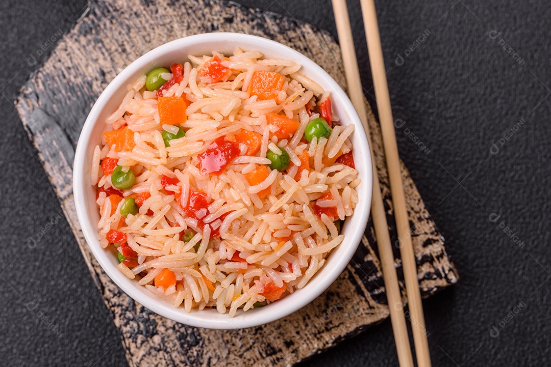 A imagem mostra um prato de arroz com vegetais, servido em uma tigela branca com um par de hashis