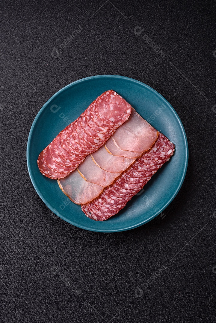 A imagem mostra uma tábua com fatias de salame e presunto, acompanhadas de temperos e especiarias como pimenta-do-reino e páprica.