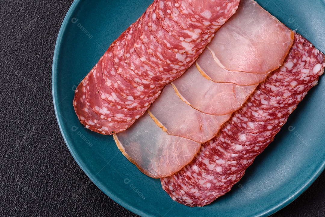 A imagem mostra uma tábua com fatias de salame e presunto, acompanhadas de temperos e especiarias como pimenta-do-reino e páprica.