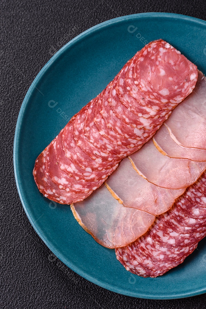 A imagem mostra uma tábua com fatias de salame e presunto, acompanhadas de temperos e especiarias como pimenta-do-reino e páprica.