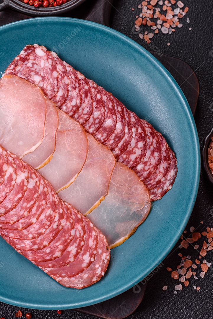 A imagem mostra uma tábua com fatias de salame e presunto, acompanhadas de temperos e especiarias como pimenta-do-reino e páprica.