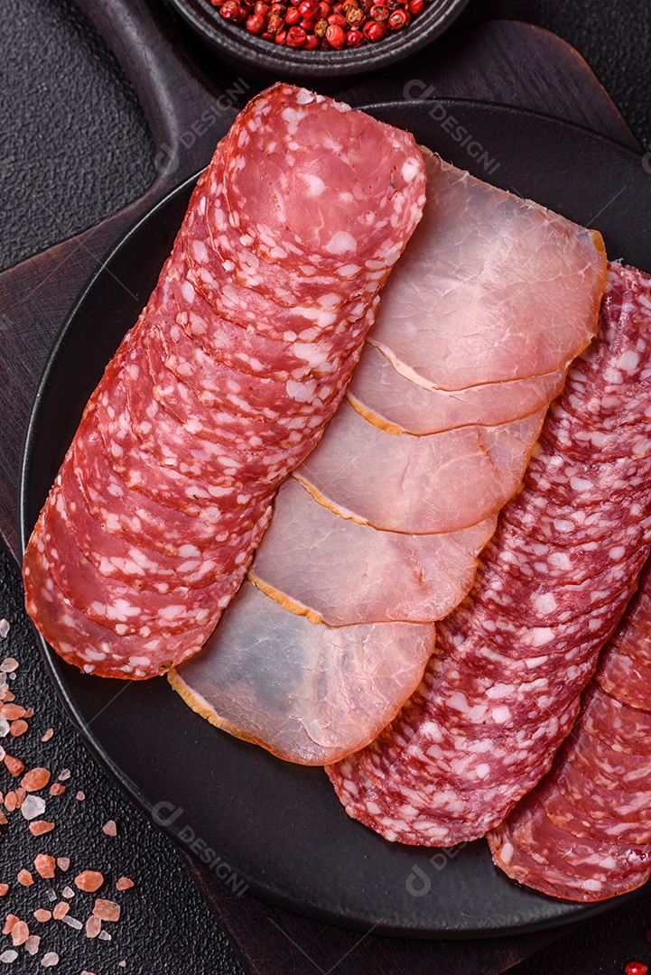 A imagem mostra uma tábua com fatias de salame e presunto, acompanhadas de temperos e especiarias como pimenta-do-reino e páprica.