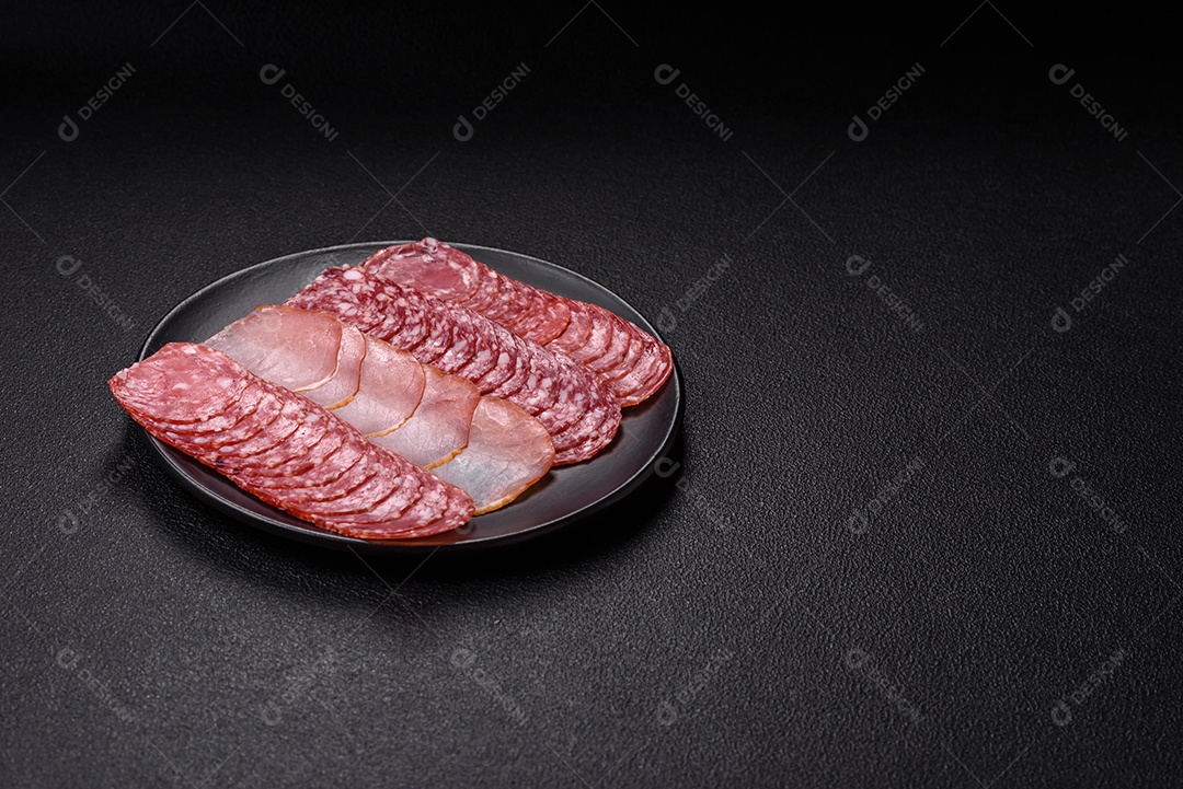 A imagem mostra uma tábua com fatias de salame e presunto, acompanhadas de temperos e especiarias como pimenta-do-reino e páprica.