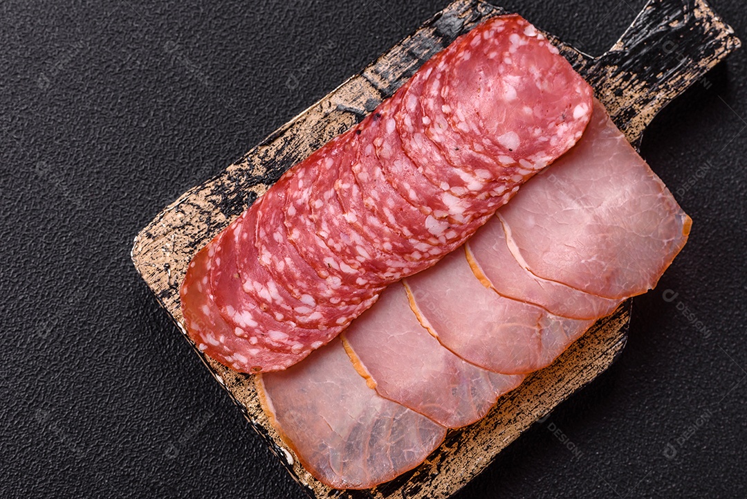 A imagem mostra uma tábua com fatias de salame e presunto, acompanhadas de temperos e especiarias como pimenta-do-reino e páprica.