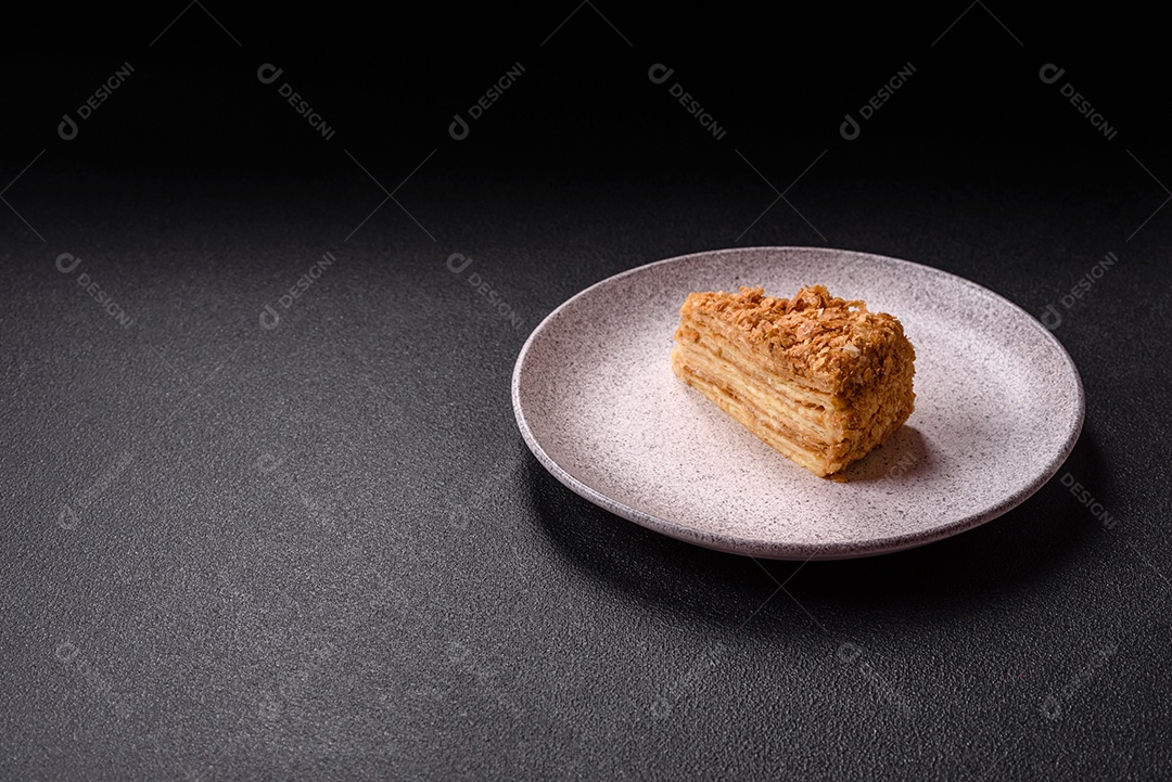 A imagem mostra um pedaço de Bolo Napoleão, uma sobremesa clássica que se assemelha ao mil-folhas.