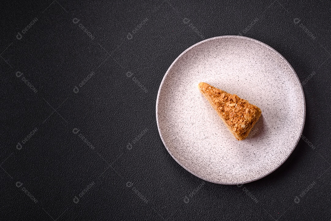 A imagem mostra um pedaço de Bolo Napoleão, uma sobremesa clássica que se assemelha ao mil-folhas.