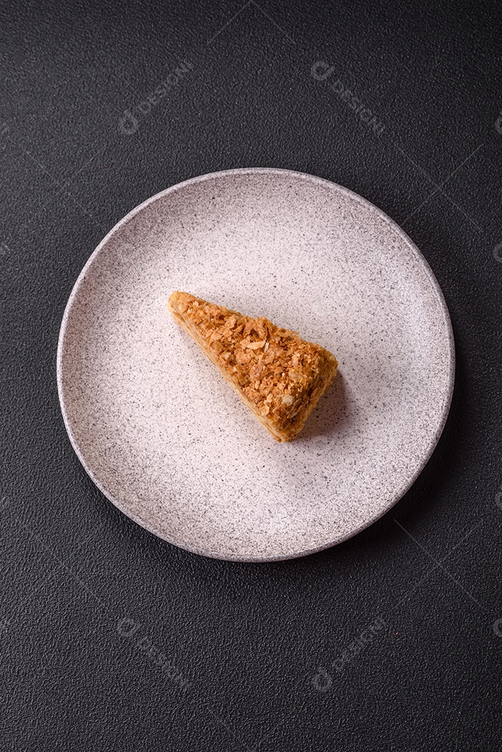 A imagem mostra um pedaço de Bolo Napoleão, uma sobremesa clássica que se assemelha ao mil-folhas.