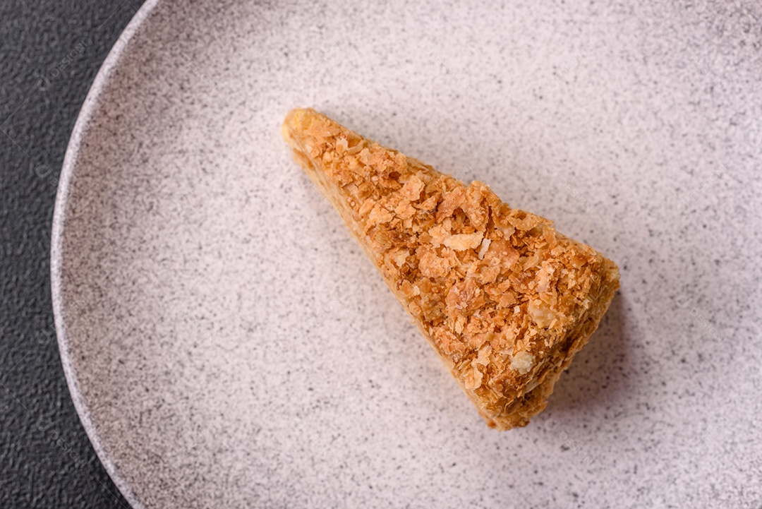 A imagem mostra um pedaço de Bolo Napoleão, uma sobremesa clássica que se assemelha ao mil-folhas.