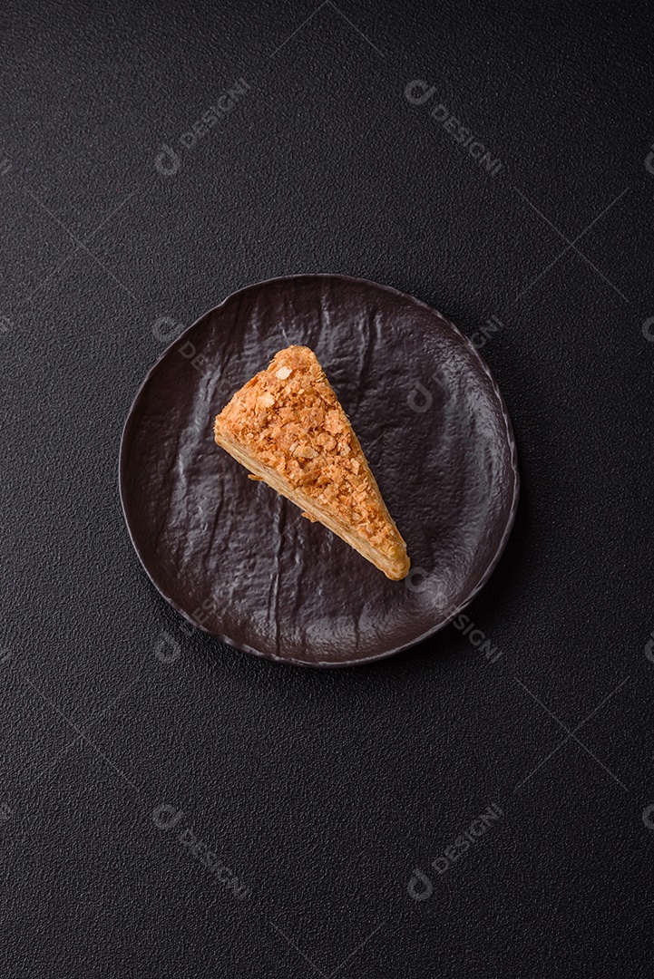 A imagem mostra um pedaço de Bolo Napoleão, uma sobremesa clássica que se assemelha ao mil-folhas.