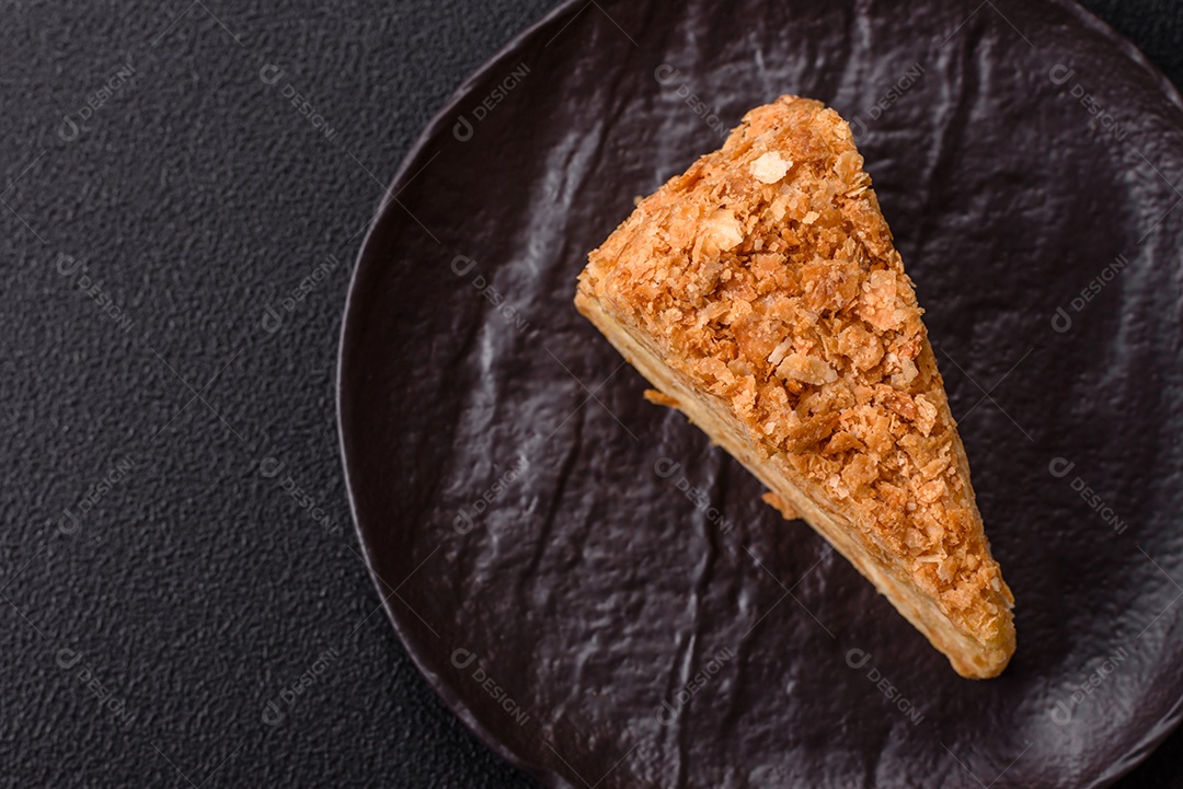 A imagem mostra um pedaço de Bolo Napoleão, uma sobremesa clássica que se assemelha ao mil-folhas.