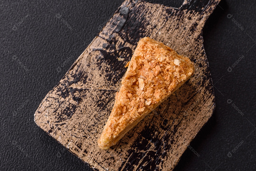 A imagem mostra um pedaço de Bolo Napoleão, uma sobremesa clássica que se assemelha ao mil-folhas.