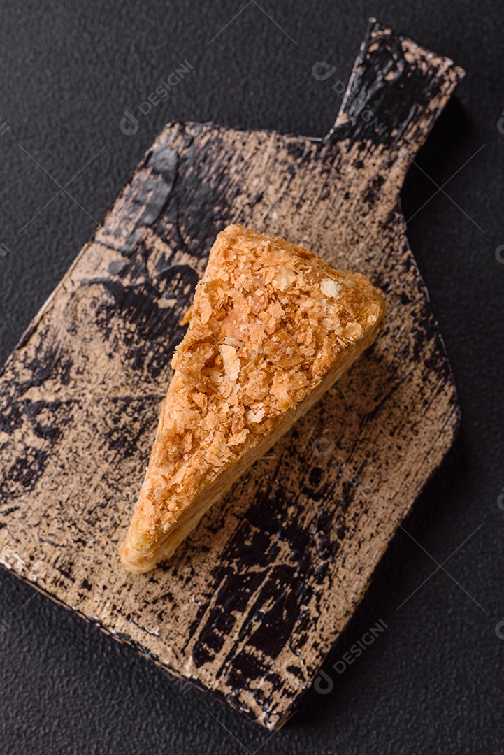 A imagem mostra um pedaço de Bolo Napoleão, uma sobremesa clássica que se assemelha ao mil-folhas.