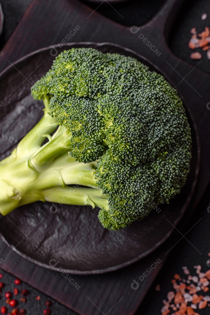 A imagem mostra um brócolis em uma tábua de corte de madeira.