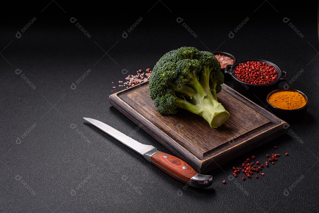 A imagem mostra um brócolis em uma tábua de corte de madeira.