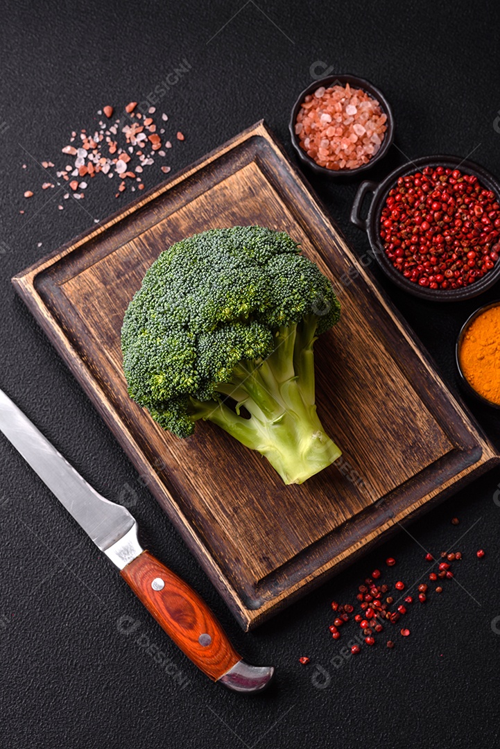 A imagem mostra um brócolis em uma tábua de corte de madeira.