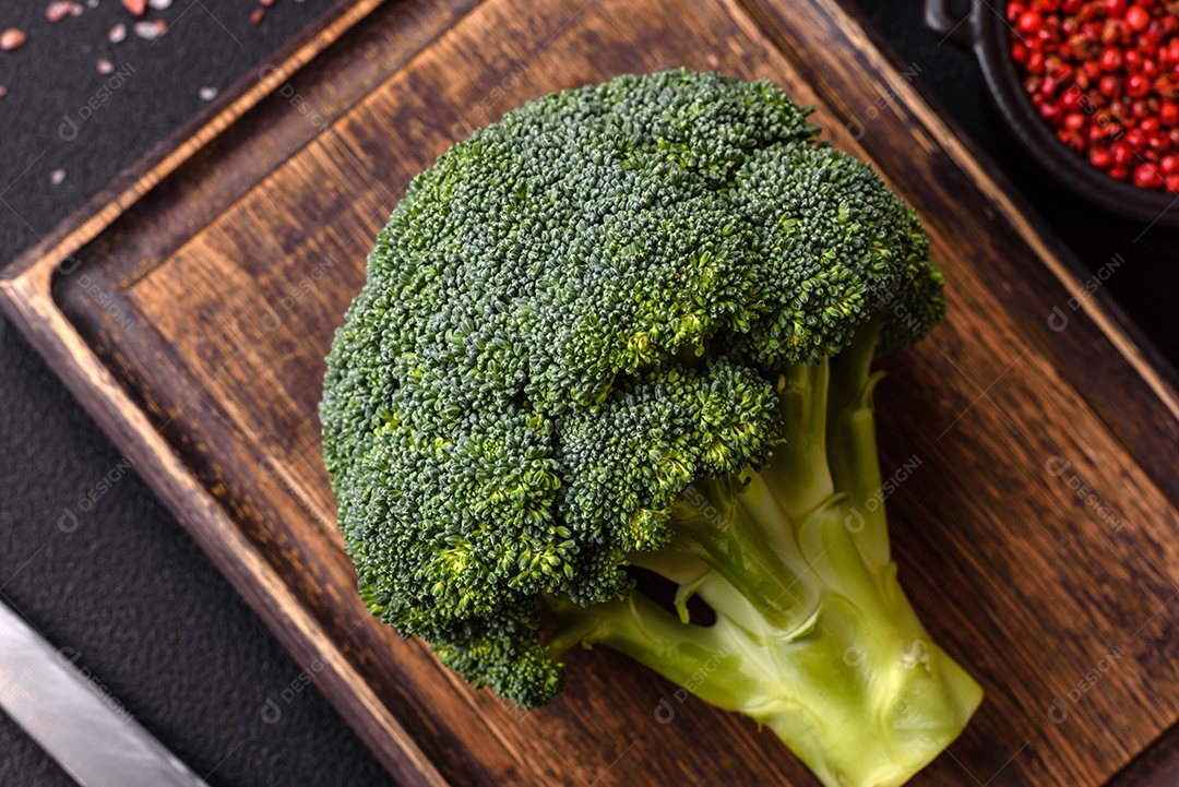 A imagem mostra um brócolis em uma tábua de corte de madeira.