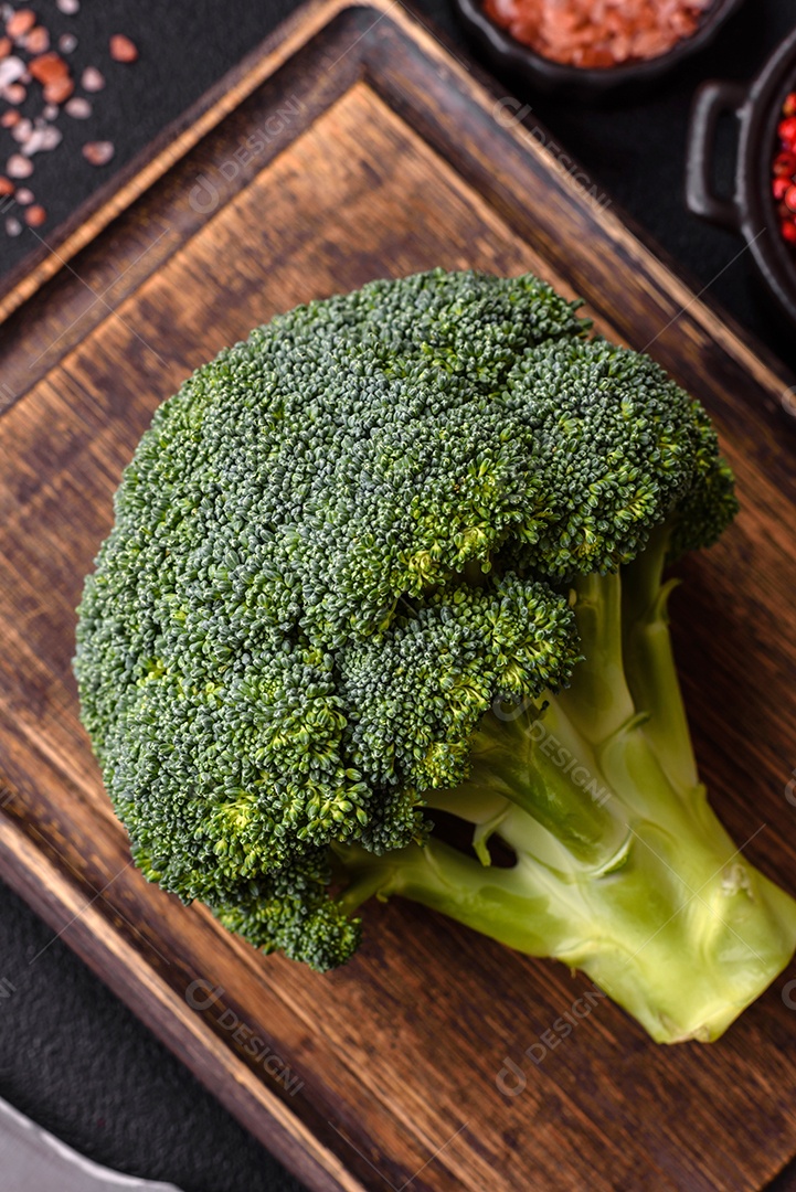 A imagem mostra um brócolis em uma tábua de corte de madeira.