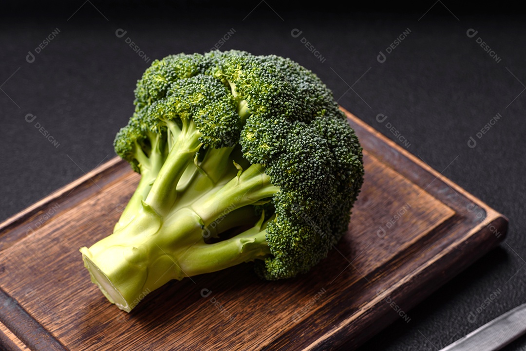 A imagem mostra um brócolis em uma tábua de corte de madeira.