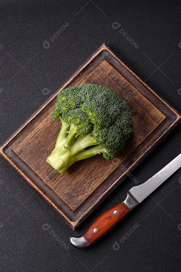 A imagem mostra um brócolis em uma tábua de corte de madeira.
