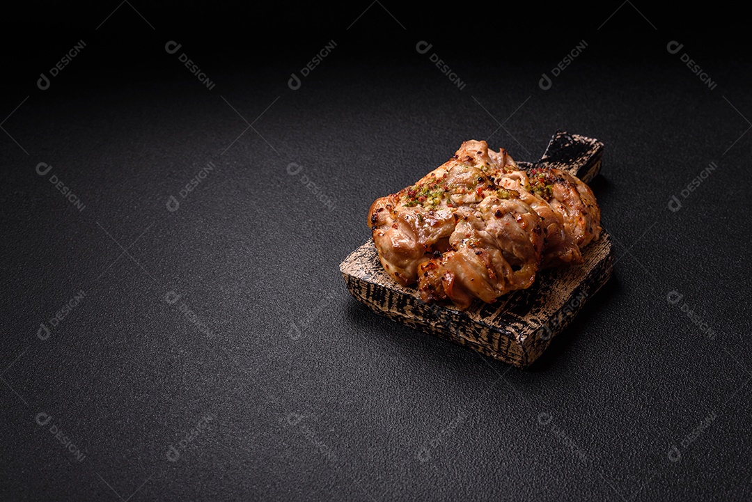 A imagem mostra sobrecoxas de frango grelhadas, servidas em um prato escuro com temperos