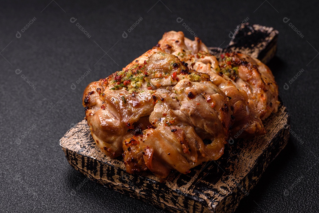 A imagem mostra sobrecoxas de frango grelhadas, servidas em um prato escuro com temperos