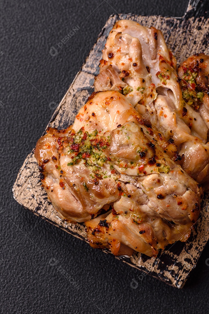 A imagem mostra sobrecoxas de frango grelhadas, servidas em um prato escuro com temperos